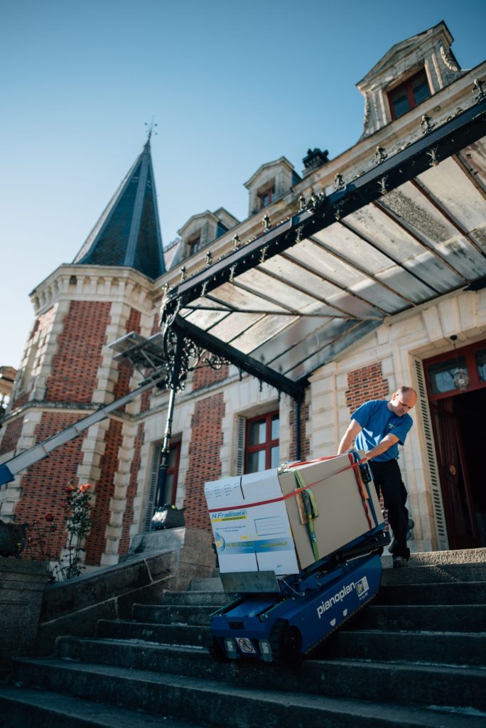 Un déménageur Fraisseix transportant un objet lourd à l'aide du Pianoplan