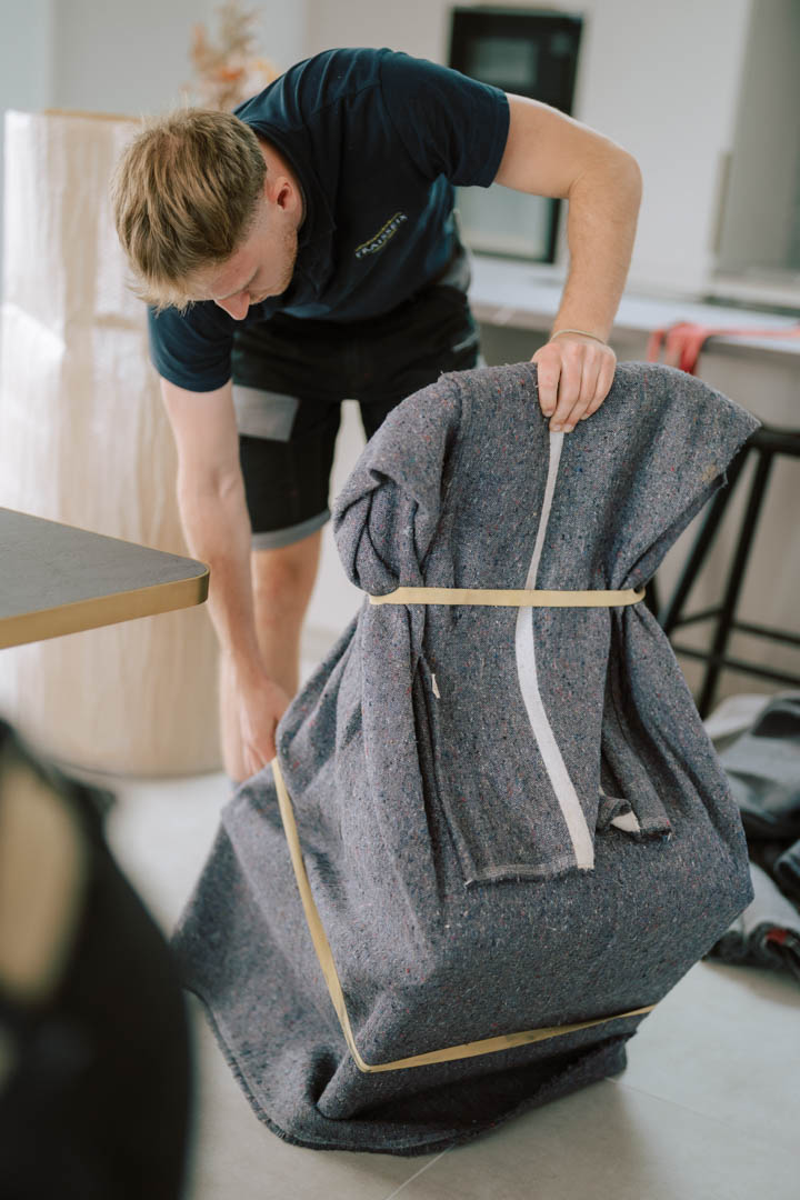 Déménageur Fraisseix transportant une chaise protégée par une couverture de déménagement